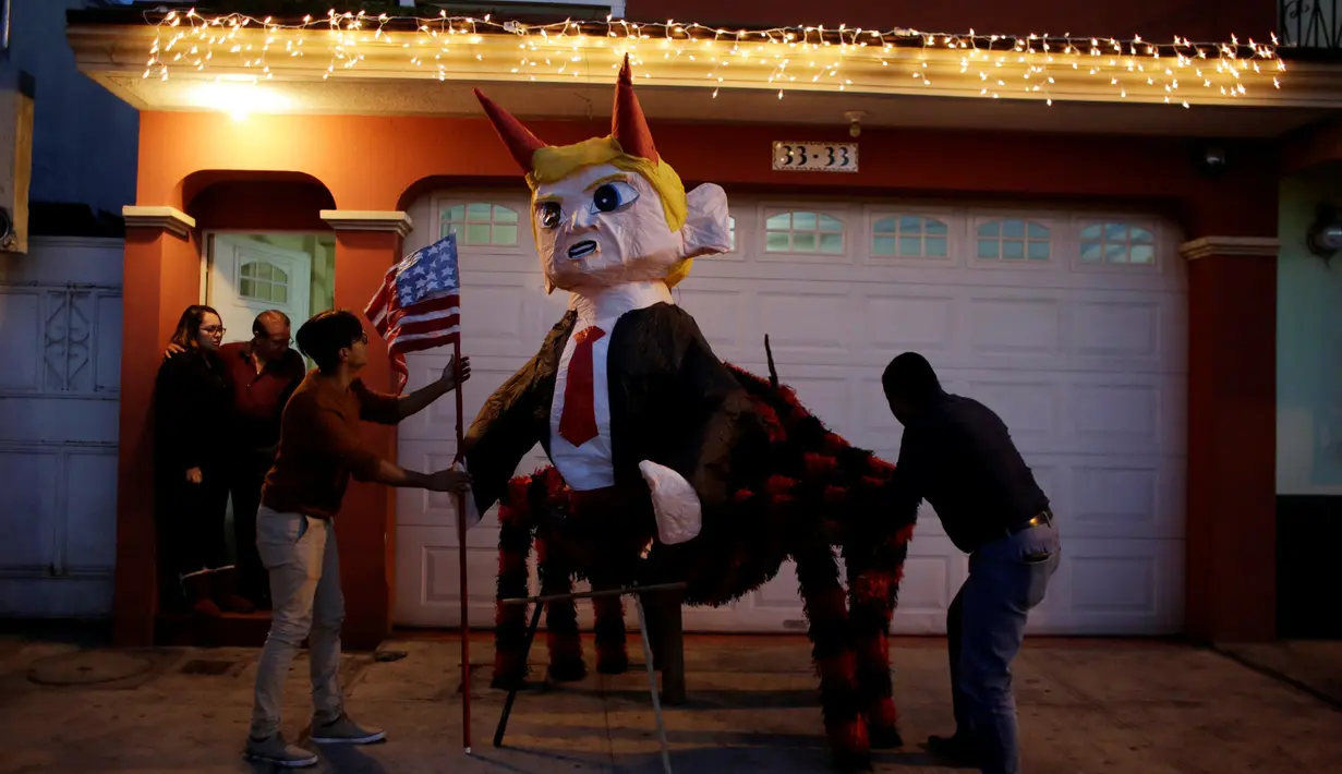 Sejumlah pria memperbaiki pinata yang berbentuk karakter Donald Trump sebelum perayaan tradisional, Pembakaran Iblis di Guatemala City, Guatemala (7/12). Pinata tersebut berbentuk Trump yang memilki tanduk dan berkaki laba-laba. (Reuters/Luis Echeverria)