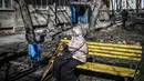 Seorang wanita menangis saat dia duduk di luar sebuah bangunan yang rusak akibat pemboman di Kota Kharkiv, Ukraina timur, 24 Februari 2022. Angkatan bersenjata Rusia melancarkan invasi militer ke Ukraina. (Aris Messinis/AFP)