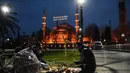 Umat Muslim berbagi Iftar, makan malam buka puasa pada hari pertama bulan puasa Ramadhan di Sultanahmet Square dengan latar belakang Masjid Biru, di Istanbul (13/4/2021). (AFP Photo/Ozan Kose)