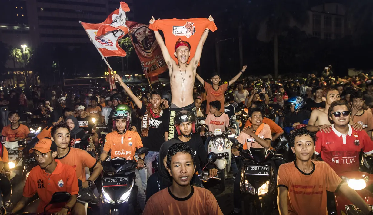 Suporter Persija Jakarta, The Jakmania, bergembira saat merayakan pesta juara Liga 1 di Bundaran Hotel Indonesia, Jakarta, Minggu (9/12). Persija unggul satu poin dari PSM Makassar di puncak klasemen. (Bola.com/Vitalis Yogi Trisna)