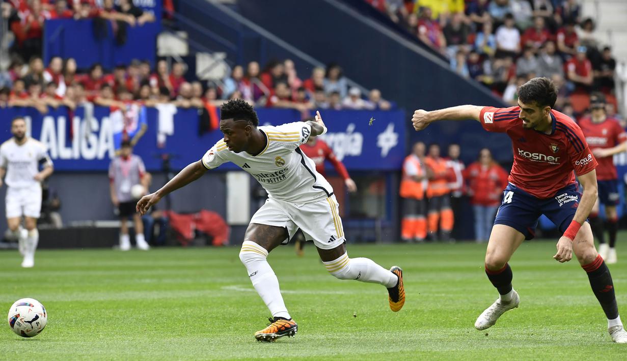 Pemain Real Madrid, Vinicius Junior, berebut bola dengan pemain Osasuna, Ruben Garcia, pada laga pekan ke-29 La Liga 2023/2024 di Stadion El Sadar, Sabtu (16/03/2024). Hasil ini membuat Real Madrid semakin perkasa di puncak klasemen sementara La Liga dengan raihan 72 angka. (AP Photo/Alvaro Barrientos)