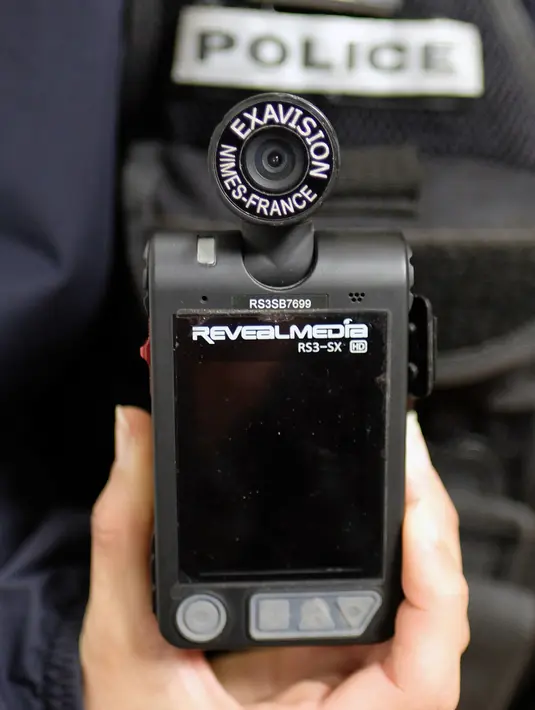 Seorang polisi menunjukkan kamera yang terpasang di tubuhnya di Marseille, Prancis, 15 Februari 2017. Penggunaan kamera tubuh kepada para anggota polisi setiap sedang berpatroli ini dilakukan untuk menekan angka kriminalitas. (BORIS HORVAT/AFP)