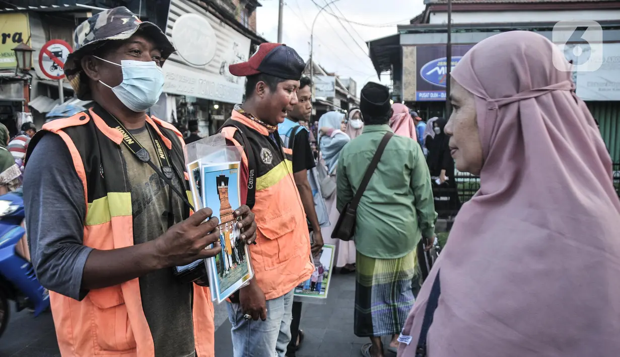 Fotografer keliling menawarkan jasanya kepada peziarah Makam Sunan Kudus, Kauman, Kabupaten Kudus, Jawa Tengah, Rabu (30/3/2022). Paguyuban Fotografer Menara Kudus sendiri telah ada sejak tahun 2000-an yang beranggotakan 30 orang. (merdeka.com/Iqbal S. Nugroho)