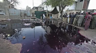 Petugas polisi dan awak media berkumpul di lokasi penyerbuan mematikan di pusat distribusi makanan dan sedekah Ramadhan di kota pelabuhan Karachi, Pakistan selatan, Jumat, 31 Maret 2023. (AP Photo/Fareed Khan)