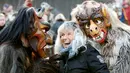 Seorang wanita berfoto bersama peserta yang mengenakan kostum iblis saat parade tardisional Perchtenlauf di Osterseeon dekat Munchen, Jerman (17/12). (Reuters/Michaela Rehle)