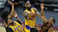Pebasket LA Lakers, LeBron James (tengah) berusaha memasukkan bola dalam laga lanjutan babak reguler NBA melawan Cleveland Cavaliers di Quicken Loans Arena, Selasa (26/1/2021). (Foto: AP Photo/Tony Dejak)