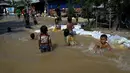 Anak-anak bermain di air banjir setelah hujan lebat di pinggiran Phnom Penh, Kamboja (26/10/2021). Kementerian Sumber Daya Air dan Meteorologi telah mengeluarkan pemberitahuan pada hari Senin tentang situasi cuaca, mengkonfirmasikan risiko banjir di 14 ibu kota dan provinsi Kamboja. (AFP Photo)