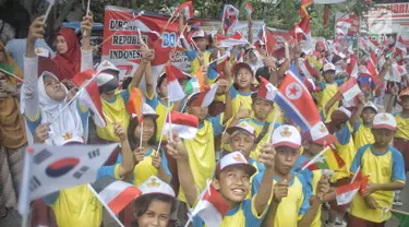 Siswa-siswi SD membawa bendera negara peserta Asian Games 2018 untuk menyambut Kirab Obor di kawasan Jati Padang, Pasar Minggu, Rabu (15/8). Mereka memenuhi jalanan untuk menyaksikan langsung Pawai Obor Asian Games 2018. (Liputan6.com/Faizal Fanani)