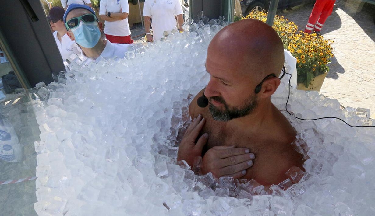 Perenang es Austria Josef Koeberl berdiri dalam kabin kaca berisi es di Melk, Austria, Sabtu (5/9/2020). Josef Koeberl berhasil memecahkan rekor dunia dengan berendam dalam es selama 2 jam, 30 menit, dan 57 detik. (AP Photo/Ronald Zak)