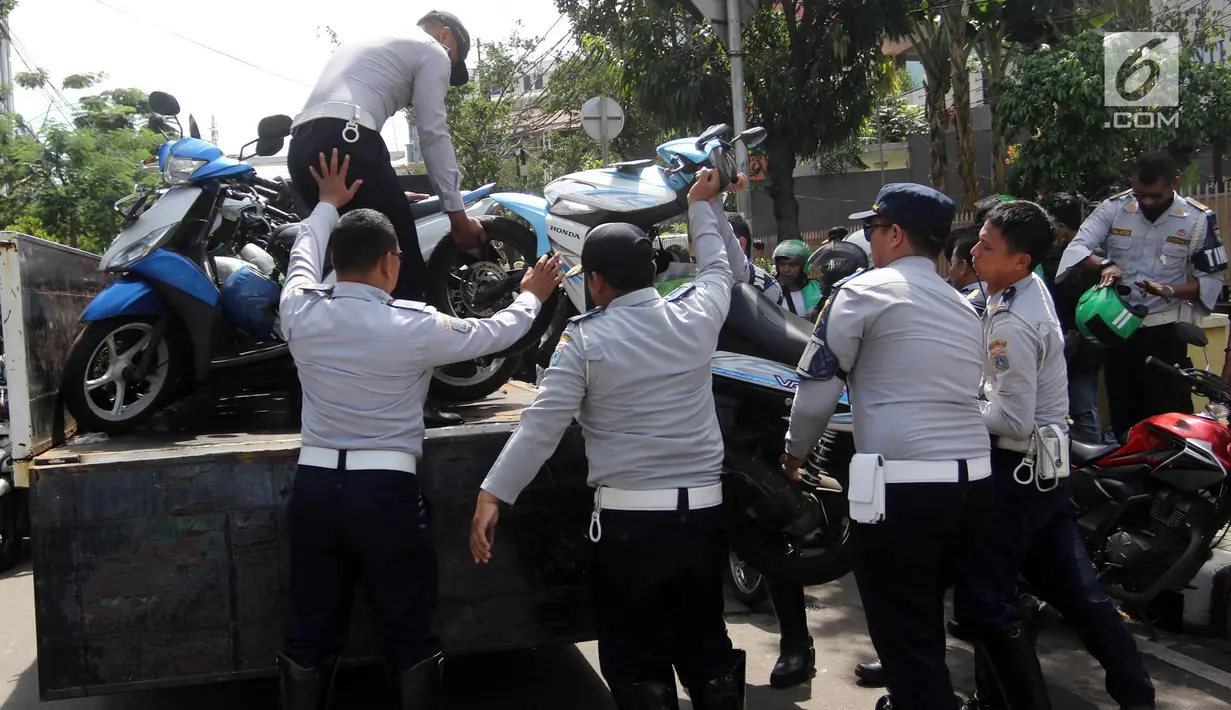 Petugas Dishub DKI Jakarta mengangkut motor saat razia parkir liar di Jalan KH Wahid Hasyim, Jakarta, Rabu (4/4). Dishub DKI Jakarta menertibkan pengendara ojek online yang memarkirkan kendaraan sembarangan di pinggir jalan. (Liputan6.com/Arya Manggala)