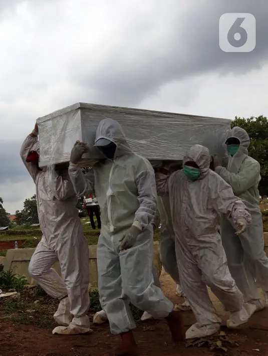 Petugas membawa peti jenazah yang akan dimakamkan dengan protokol COVID-19 di area khusus TPU Srengseng Sawah, Jakarta, Kamis (14/1/2021). TPU ini digunakan untuk memakamkan jenazah dengan protokol COVID-19 karena TPU Tegal Alur dan Pondok Ranggon sudah penuh. (Liputan6.com/Helmi Fithriansyah)