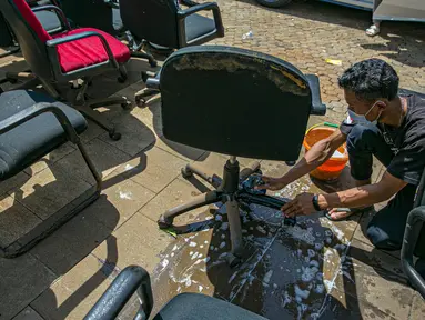 Karyawan membersihkan peralatan kantor pascabanjir di salah satu bank swasta di Kemang, Jakarta, Selasa (23/2/2021). Karyawan pertokoan, perkantoran, hingga perbankan mulai membersihkan sisa lumpur dari banjir yang melanda kawasan tersebut pada 20 Februari 2021 lalu. (Liputan6.com/Faizal Fanani)
