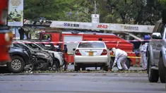 Pasukan keamanan dan petugas forensik memeriksa lokasi ledakan di sebuah jalan dekat gedung parlemen di Kampala, Uganda (16/11/2021).  Dilaporkan BBC, Rabu (17/11/2021), tiga orang pelaku bom bunuh diri itu disebut naik motor.  (AP Photo/Hajarah Nalwadda)