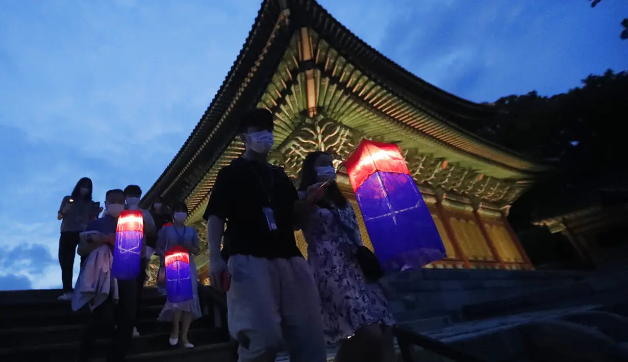 Pengunjung memegang lentera tradisional Korea berjalan-jalan selama Tur Cahaya Bulan di Istana Changdeokgung di Seoul, Korea Selatan, Kamis, (13/8/2020). Istana dibuka kembali pada Kamis setelah ditutup selama dua bulan karena pandemi Covid-19. (AP Photo/Ahn Young-joon)