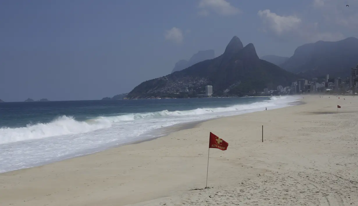 Bendera peringatan merah menghiasi hamparan pantai Arpoador yang ditutup karena diberlakukannya kembali pembatasan pandemi COVID-19 di Rio de Janeiro, Brasil, Sabtu (20/3/2021). Rio de Janeiro menutup pantai-pantainya yang terkenal untuk menekan angka kasus COVID-19. (AP Photo/Bruna Prado)