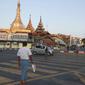 Orang-orang menyeberang jalan dekat Pagoda Sule di Yangon, Myanmar pada Senin (1/2/2021). Militer Myanmar resmi merebut kekuasaan pemerintah usai menahan Kanselir Aung San Suu Kyi dan Presiden Myint pada Senin pagi (1/2). (AP Photo/Thein Zaw)