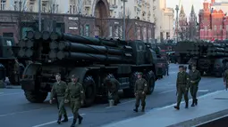 Sejumlah tentara Rusia berjalan di dekata kendaraan militer yang memenuhi jalanan saat melakukan latihan untuk parade militer Hari Kemenangan di Moskow, Rusia (3/5). (AP Photo / Pavel Golovkin)