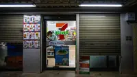 Seorang pegawai minimarket 7-Eleven yang biasanya buka 24 jam mengunci pintu gerai jelang pembatasan jam malam untuk mengurangi penyebaran COVID-19 di Bangkok, Thailand, Senin (19/7/2021). Jumlah kematian akibat COVID-19 di Thailand mencapai 3.610 kasus sejak pandemi dimulai. (Candida NG/AFP)