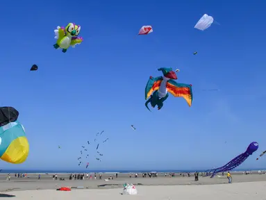 Orang-orang menerbangkan layang-layang berbagai bentuk dan warna dalam Festival Layang-Layang Internasional ke-32 di pantai Berck-sur-Mer, Prancis utara, 18 April 2018. Kegiatan internasional ini berlangsung hingga 22 April 2018. (Denis Charlet/AFP)