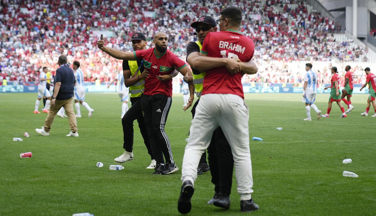 Petugas keamanan bekerja ekstra keras saat menangkap para suporter yang nekat menerobos lapangan saat Argentina berhadapan dengan Maroko pada laga grup B  Olimpiade Paris 2024. (AP Photo/Silvia Izquierdo)