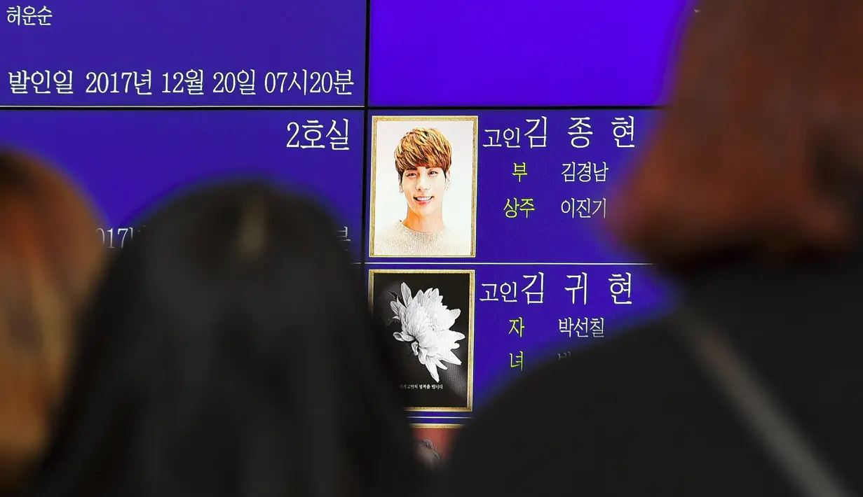 Para fans memandangi foto Jonghyun SHINee di papan elektronik di luar rumah duka Seoul Asan Hospital, Korea Selatan, Selasa (19/12). Jonghyun SHINee dikabarkan meninggal dunia karena bunuh diri menghirup karbon monoksida berlebih. (JUNG Yeon-Je / AFP)