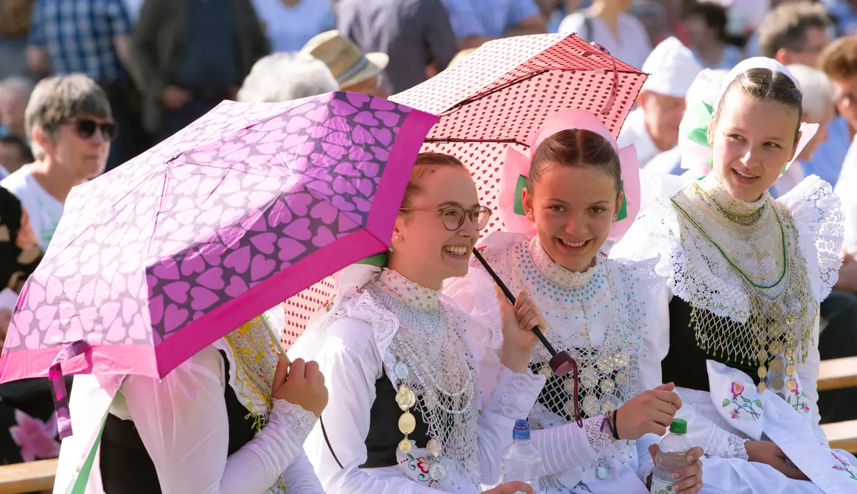 Sejumlah wanita berpakaian tradisional Sorbs memegang payung selama prosesi ritual Whit Monday di Rosenthal, Jerman, Senin (10/6/2019). Whit Monday menjadi hari libur nasional di Jerman dan banyak negara lain. (AP Photo/Jens Meyer)
