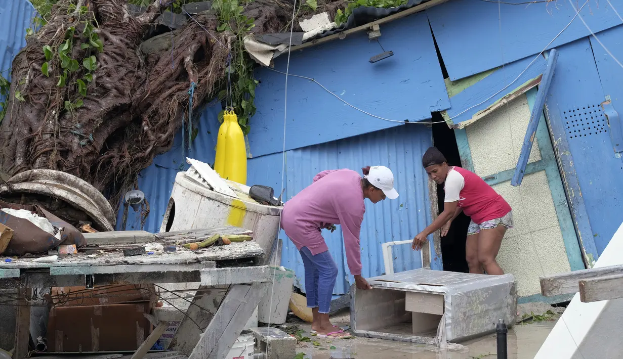 Yesenia Martinez (kiri) dan Dilcia Figaro mengambil barang-barang yang tercecer usai diterjang Badai Fiona di lingkungan berpenghasilan rendah Kosovo di Veron de Punta Cana, Republik Dominika (19/9/2022). Badai itu berada sekitar 80 mil tenggara Pulau Grand Turk dan diperkirakan akan menguat ke Kategori 3 saat melintasi perairan Karibia yang hangat menuju Turks dan Caicos.  (AP Photo/Ricardo Hernandez)