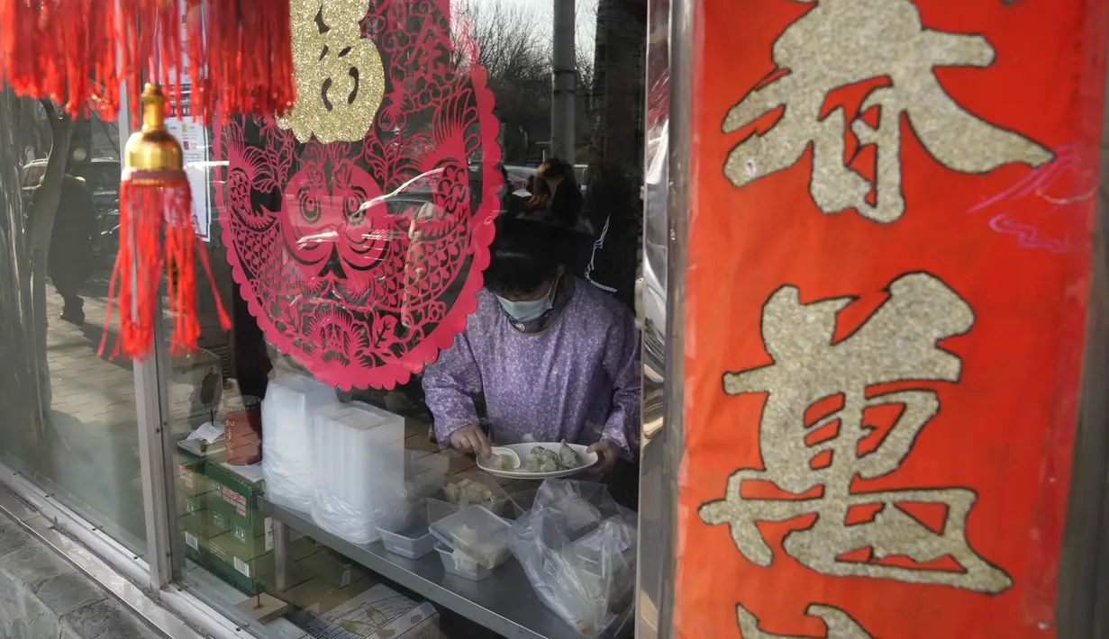 Seorang pekerja mengemas pangsit untuk pelanggan di sebuah restoran selama hari titik balik matahari musim dingin di Beijing, China, Selasa (21/12/2021). Pangsit adalah makanan festival selama hari titik balik matahari musim dingin. (AP Photo/Ng Han Guan)