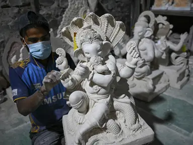 Perajin mengerjakan patung dewa Hindu berkepala gajah Lord Ganesha di sebuah lokakarya menjelang festival Ganesh Chaturthi di Mumbai (12/8/2021). Festival Ganesh Chaturthi adalah perayaan kelahiran Ganesha, dewa kebijaksanaan, kemakmuran, dan keberuntungan Hindu. (AFP/Punit Paranjpe)