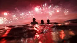 Sejumlah orang saat melihat kembang api yang meledak mengiasi langit di pantai Copacabana saat perayaan Tahun Baru 2016 di Rio de Janeiro, Brasil, (1/1/2016). (REUTERS/Ricardo Moraes)