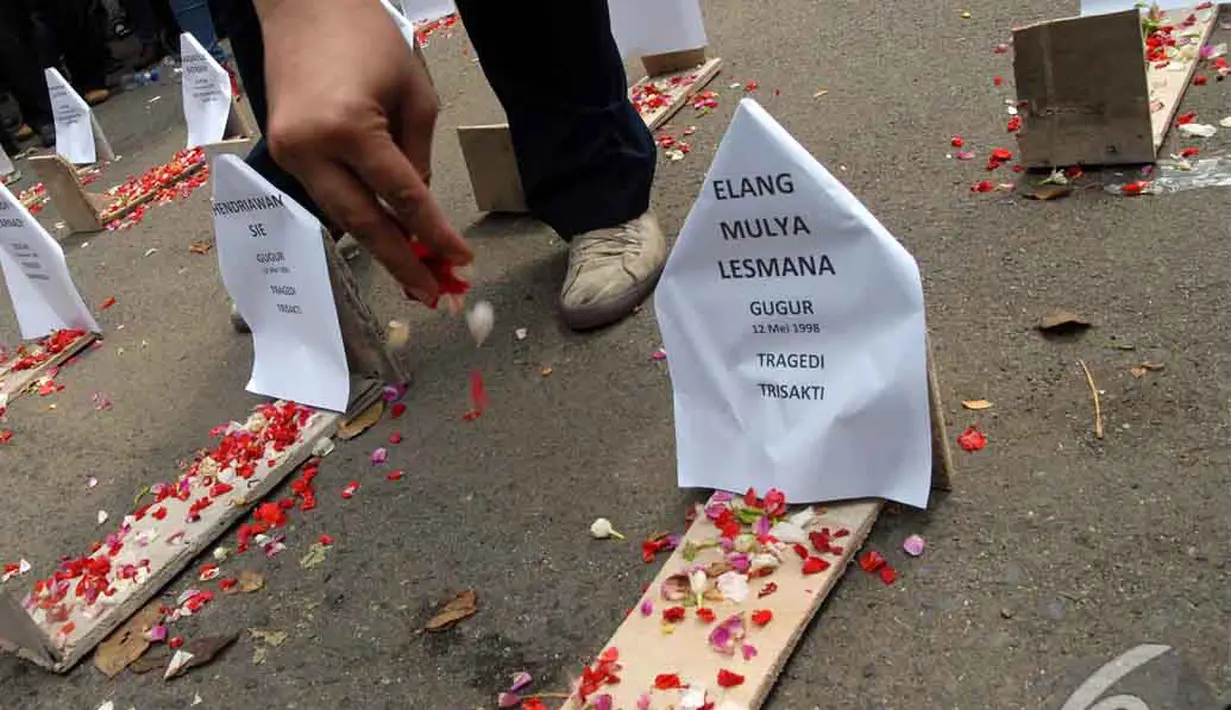 Para pendemo menaburkan bunga pada nisan-nisan yang mereka letakkan di jalan raya. Aksi ini sebagai sindiran kepada pemerintah yang tak kunjung menuntaskan kasus tragedi 98, Jakarta, Selasa (24/06/2014) (Liputan6.com/Faisal R Syam)