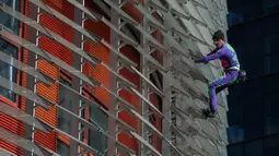 Pendaki pencakar langit, Alain Robert, yang juga dikenal sebagai 'Spiderman Prancis' memanjat Menara Agbar setinggi 144 meter di Barcelona, Rabu (4/3/2020). Aksi yang dilakukan tanpa menggunakan alat pengaman itu sebagai bentuk protes terhadap kepanikan atas epidemi virus corona. (LLUIS GENE/AFP)