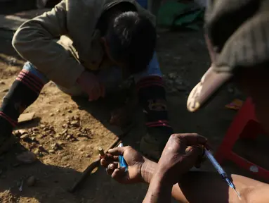 Dua penambang menyuntikkan heroin di Tambang batu giok di Hpakant, Myanmar, 29 November 2015. Kecanduan narkotika sudah merabak pada penambang batu giok untuk digunakan dengan alasan agar kuat mencari & menemukan gumpalan batu mulia (REUTERS/Soe Zeya Tun)