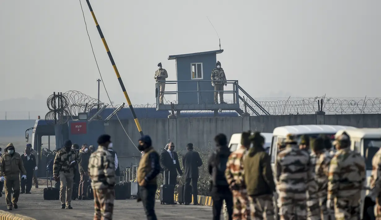 Petugas keamanan berjaga ketika warga negara India diangkut dengan bus keluar dari Bandara Internasional Indira Gandhi setelah dievakuasi dari kota Wuhan di Cina, di New Delhi (1/2/2020). (AFP/Money Sharma)