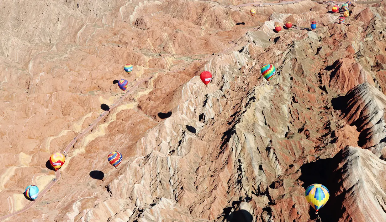 Sejumlah balon udara terbang di atas Taman Geologi Nasional Danxia di Zhangye, Provinsi Gansu, China barat laut, pada 26 Juli 2020. Sebuah festival balon udara internasional dibuka di Zhangye pada Minggu (26/7). Total 100 balon udara akan ditampilkan dalam festival tersebut. (Xinhua/Cheng Lin)