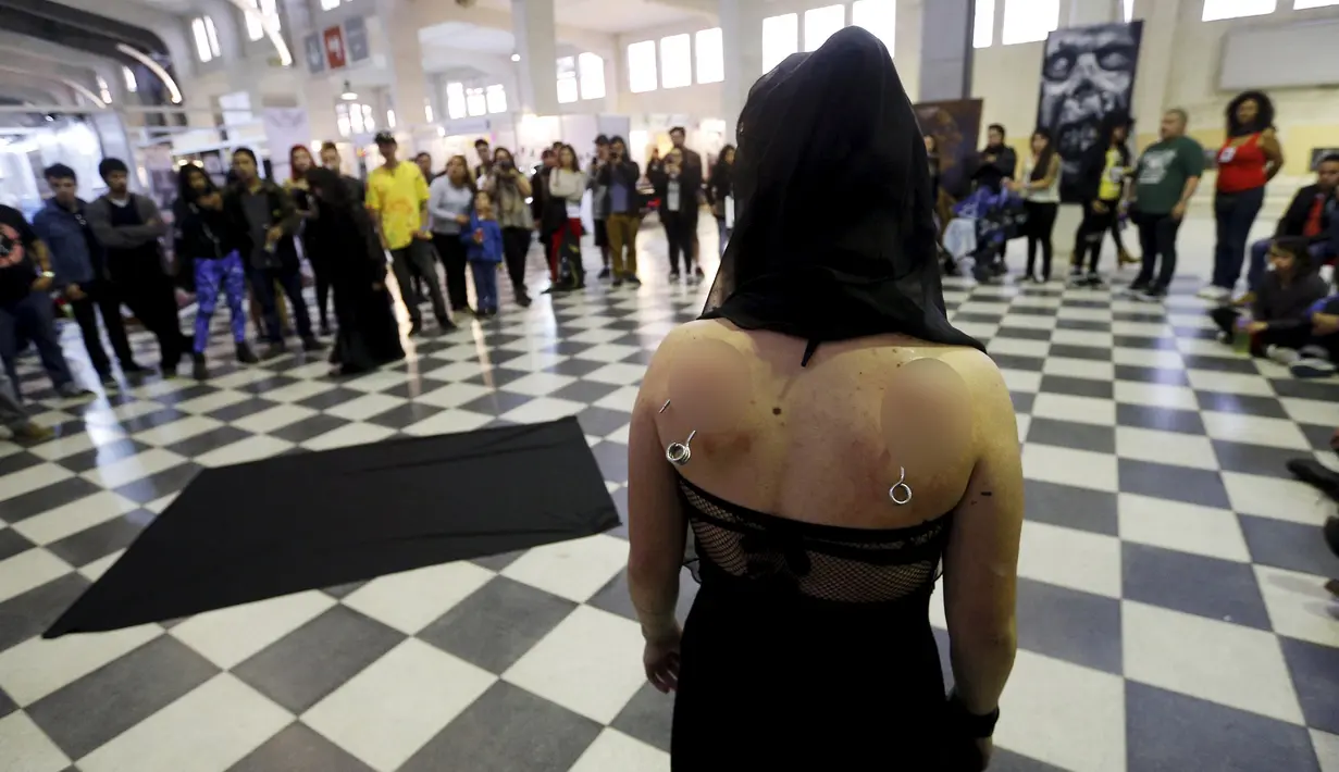 Wanita dikaitkan sebuah besi di punggungnya untuk melakukan aksi selama Tattoo and Suspension Convention di Valparaiso, Chili, (8/11/2015). Acara ini merupakan kegiatan untuk para penyuka tato dan modifikasi tubuh di Chili.  (REUTERS/Rodrigo Garrido)
