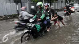 Sejumlah anak membantu pengendara motor yang mogok akibat menerobos genangan air di Pejaten Raya, Jakarta, Selasa (4/10). Akibat curah hujan yang tinggi menyebabkan sejumlah titik di Jakarta Selatan tergenang air. (Liputan6.com/Yoppy Renato)