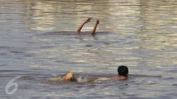 Dua anak berenang di Kanal Banjir Barat, Jakarta, Kamis (26/11/2015). Dalamnya kali tidak menjadi penghalang bagi anak-anak tersebut untuk tetap bermain, meskipun berbahaya bagi keselamatan mereka. (Liputan6.com/Immanuel Antonius)