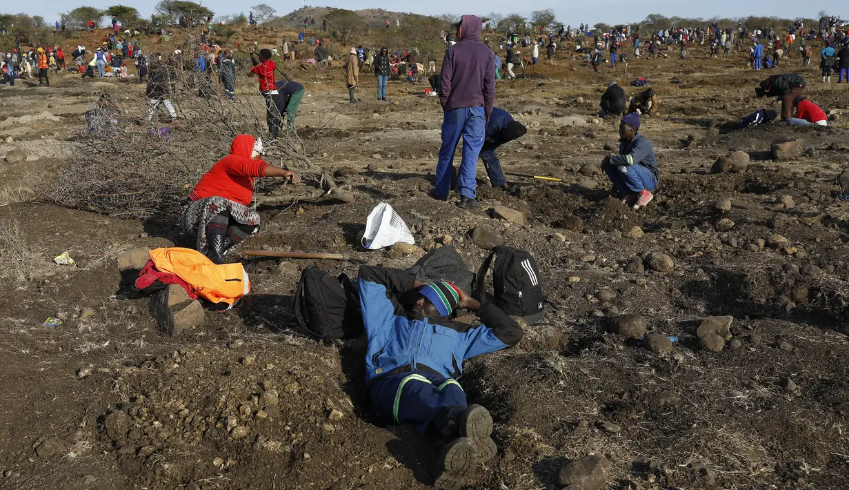 Seorang pria beristirahat sementara yang lain menggali untuk mencari apa yang mereka yakini sebagai berlian setelah penemuan batu tak dikenal di desa KwaHlathi dekat Ladysmith, Afrika Selatan (15/6/2021). (AFP/Phill Magakoe)