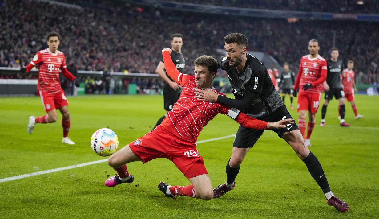 Pemain Bayern Munchen, Thomas Mueller, berebut bola dengan pemain SC Freiburg, Manuel Gulde, dalam laga babak perempat final DFB Pokal di Allianz Arena, Rabu (05/04/2023). Bayern Munchen secara mengejutkan tersingkir dari gelaran DFB Pokal setelah takluk 1-2 atas Freiburg. (AP Photo/Matthias Schrader)