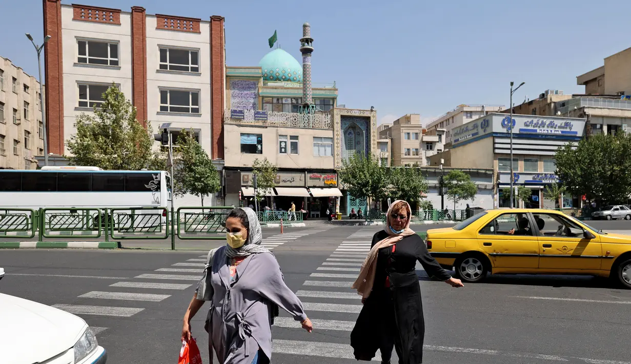PeRempuan Iran menyeberang jalan di pusat kota Teheran ketika pihak berwenang memperketat pembatasan, Selasa (20/7/2021). Iran memberlakukan lockdown di Teheran dan provinsi terdekat setelah kasus infeksi Covid-19 mencapai rekor tertingginya selama wabah kelima. (ATTA KENARE/AFP)