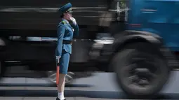 Seorang polisi wanita mengatur lalu lintas di sebelah truk yang melintas di Pyongyang, Korea Utara (5/6). Para polisi wanita ini harus meninggalkan profesi mereka jika mereka menikah dan akan pensiun ketika memasuki usia 26 tahun. (AFP Photo/Ed Jones)