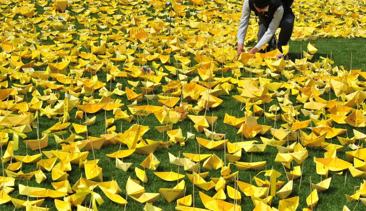 Seorang mahasiswa menaruh kapal kertas kuning yang disusun menjadi bentuk hati pada peringatan bagi korban feri 'Sewol' di Balai Kota Seoul, Rabu (7/5/14). (AFP PHOTO/JUNG YEON-JE)