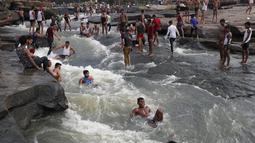 Orang-orang bermain di perairan Air Terjun Rajdari pada hari musim panas yang terik di distrik Chandauli, negara bagian Uttar Pradesh, India (28/6/2021).  Air Terjun Rajdari adalah tempat piknik yang populer bagi orang-orang di sekitar area tersebut pada musim panas. (AP Photo/Rajesh Kumar Singh)