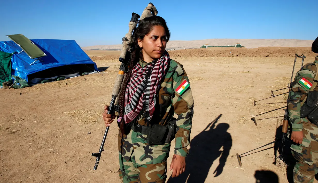 Seorang pejuang wanita Iran-Kurdi berpakaian militer lengkap dengan senjatanya saat  pertempuran melawan kelompok radikal Negara Islam (ISIS) di Bashiqa, dekat Mosul, Irak, Kamis (3/11). (Reuters/Ahmed Jadallah)