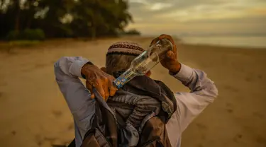 Tengku Mohamad Ali Mansor menyimpan botol kaca yang dia temukan di pantai dalam ranselnya saat matahari terbit di sebuah pantai di desa Mangkuk di distrik Setiu negara bagian Terengganu Malaysia timur pada 12 September 2020. (AFP/Mohd Rasfan)