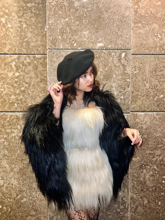 Fuji memakai outer bulu-bulu dan topi warna hitam yang memberi kesan elegan. Gaya Fuji semakin glamor dan manis dengan memakai kalung putih. (instagram/fuji_an)