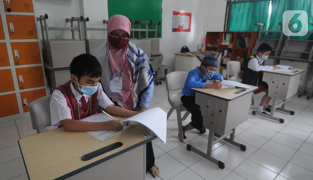 Guru mangawasi murid saat kegiatan  KSN  seleksi Tingkat SD/ MI Kecamatan Cinere  mata pelajaran IPA di SDIT MU, Depok, jawa Barat, Sabtu (6/3/2021). Pelaksanaan KSN tahun ini dilaksanakan secara tatap muka dengan menerapkan protokol kesehatan. (merdeka.com/Arie Basuki)