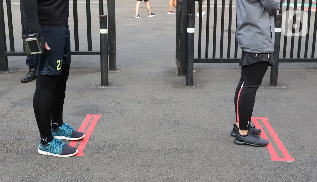 Batas jarak fisik untuk warga antre masuk lingkar Stadion Utama Gelora Bung Karno, Jakarta, Sabtu (6/6/2020). SUGBK dibuka kembali untuk kegiatan olahraga masyarakat dengan menerapkan protokol kesehatan pasca keputusan Pemprov DKI Jakarta menerapkan PSBB transisi. (Liputan6.com/Helmi Fithriansyah)