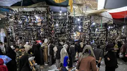 Orang-orang memilih sepatu dan sandal di pasar terbuka di ibu kota Yaman, Sanaa (2/5/2021). Umat Muslim di Yaman memenuhi pasar menjelang liburan Idul Fitri yang menandai akhir bulan suci Ramadhan. (AFP/Mohammed Huwais)